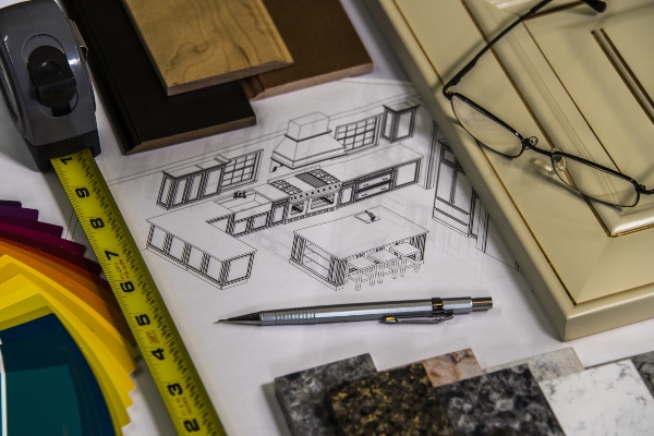 Slats of wood, a tape measure, and kitchen remodeling design plans sit on top of a kitchen counter.