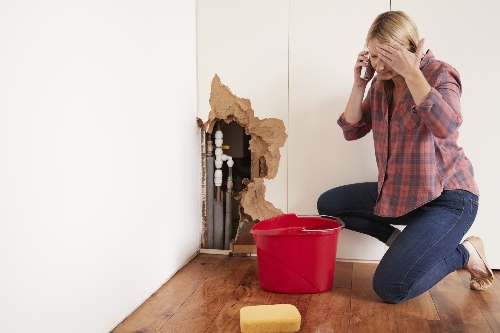 A homeowner struggles with a plumbing systems pipes behind the drywall. 