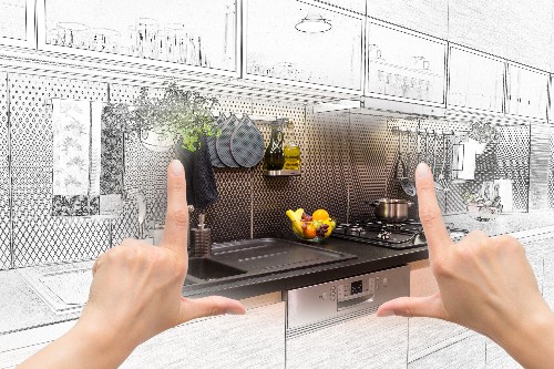 A person holds up their hands over a colored in section of a kitchen design sketch done by a professional kitchen design company.